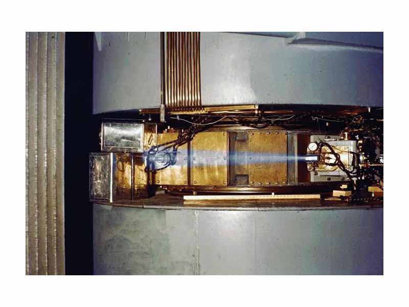 60-inch cyclotron, circa 1939, showing a beam of accelerated ions (likely protons or deuterons) escaping the accelerator and ionizing the surrounding air causing a blue glow. This phenomenon of air ionization is analogous to the one responsible for producing the blue flash infamously noted by witnesses of criticality accidents. Though the effect is often mistaken for Cherenkov radiation, this is not the case.